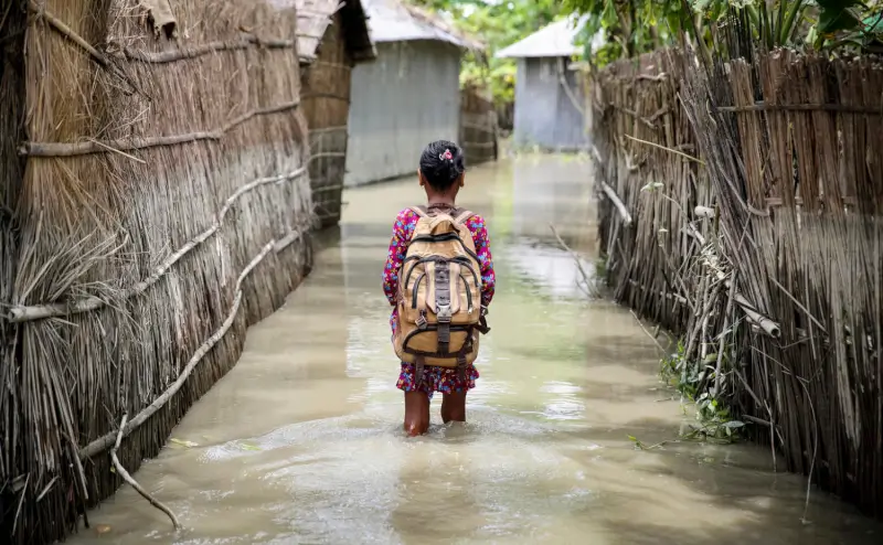 A child wades through water on her way to school in Kurigram district of northern Bangladesh during floods in August 2016 - Akash/Panos Pictures/UNICEF 