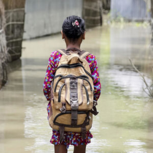 A child wades through water on her way to school in Kurigram district of northern Bangladesh during floods in August 2016 - Akash/Panos Pictures/UNICEF 